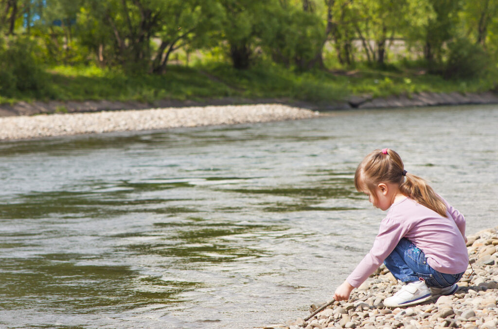 Una bambina gioca in riva al fiume