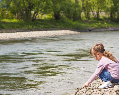 Una bambina gioca in riva al fiume