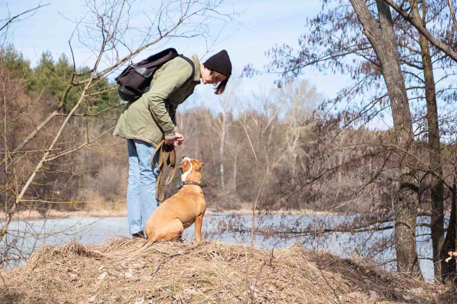 Una ragazza insieme al suo cane lungo il fiume