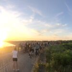 Un gruppo di persone attraversano in bicicletta il Parco del Delta del Po al tramonto