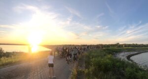 Un gruppo di persone attraversano in bicicletta il Parco del Delta del Po al tramonto