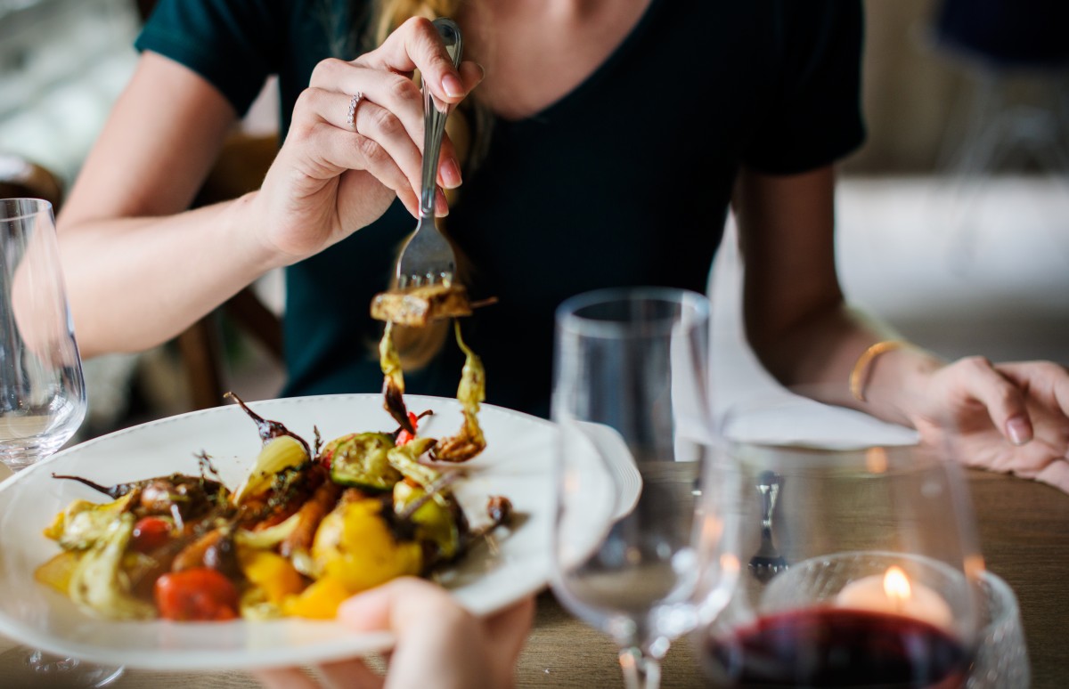 Una donna mangia delle verdure in un piatto al ristorante