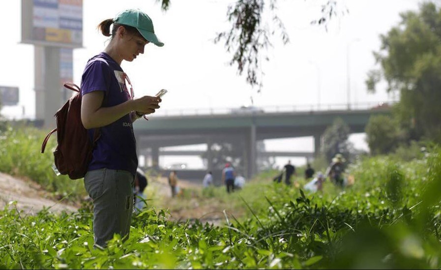 Una ragazza fotografa con lo smartphone delle specie vegetali nell'ambito della Nature city challenge