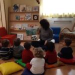 Bambini in cerchio ascoltano la lettura di una storia, progetto "Leggere: forte!"