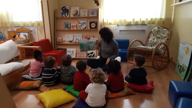 Bambini in cerchio ascoltano la lettura di una storia, progetto "Leggere: forte!"