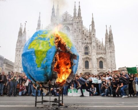 Un pianeta di cartapesta in fiamme davanti al Duomo di Milano