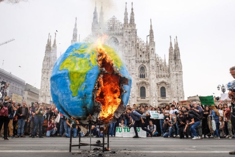 Un pianeta di cartapesta in fiamme davanti al Duomo di Milano