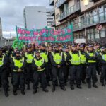 Glasgow, 3 novembre 2021. La polizia blocca la marcia di Extinction Rebellion che si dirigeva nei paraggi della Cop26. Lo striscione gioca sul doppio senso della parola "cop", in inglese poliziotto: quante cop (e quanti "cops") ci vogliono per arrestare il cambiamento climatico?