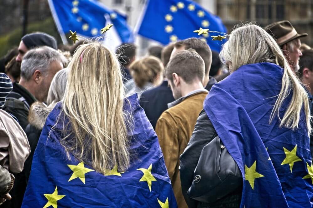 manifestanti vestiti con bandiere dell'Unione Europea