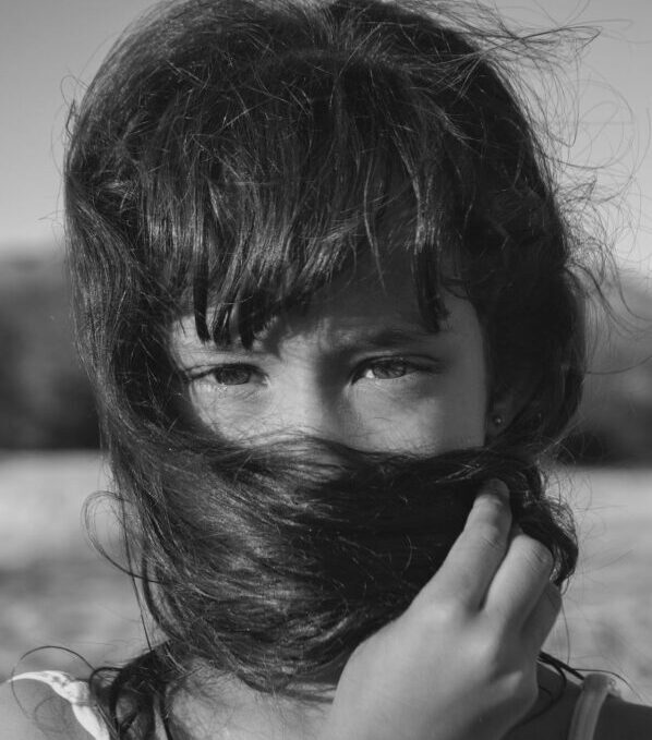 Una bambina si copre la bocca con i capelli