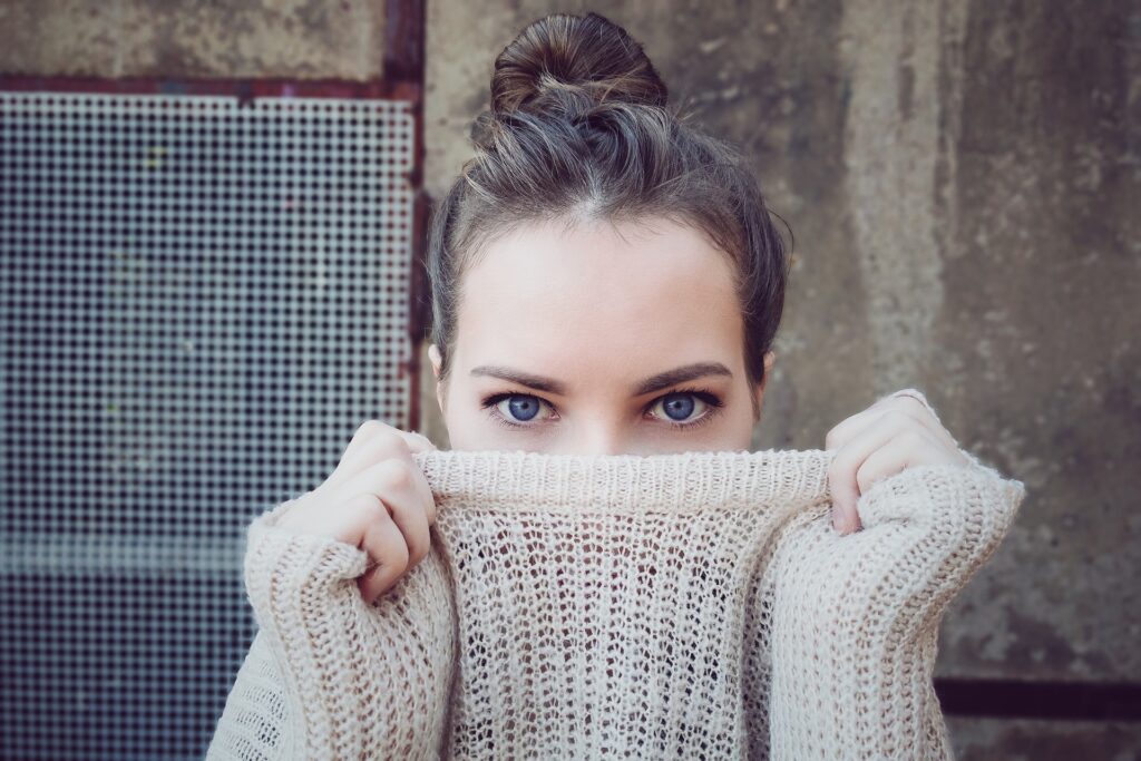 Una donna con un maglione di lana nasconde metà viso nel collo del maglione