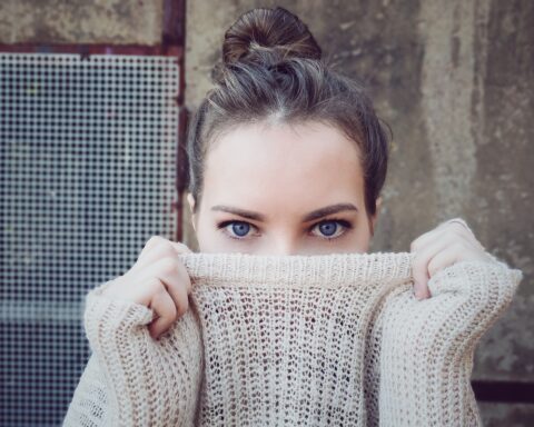 Una donna con un maglione di lana nasconde metà viso nel collo del maglione