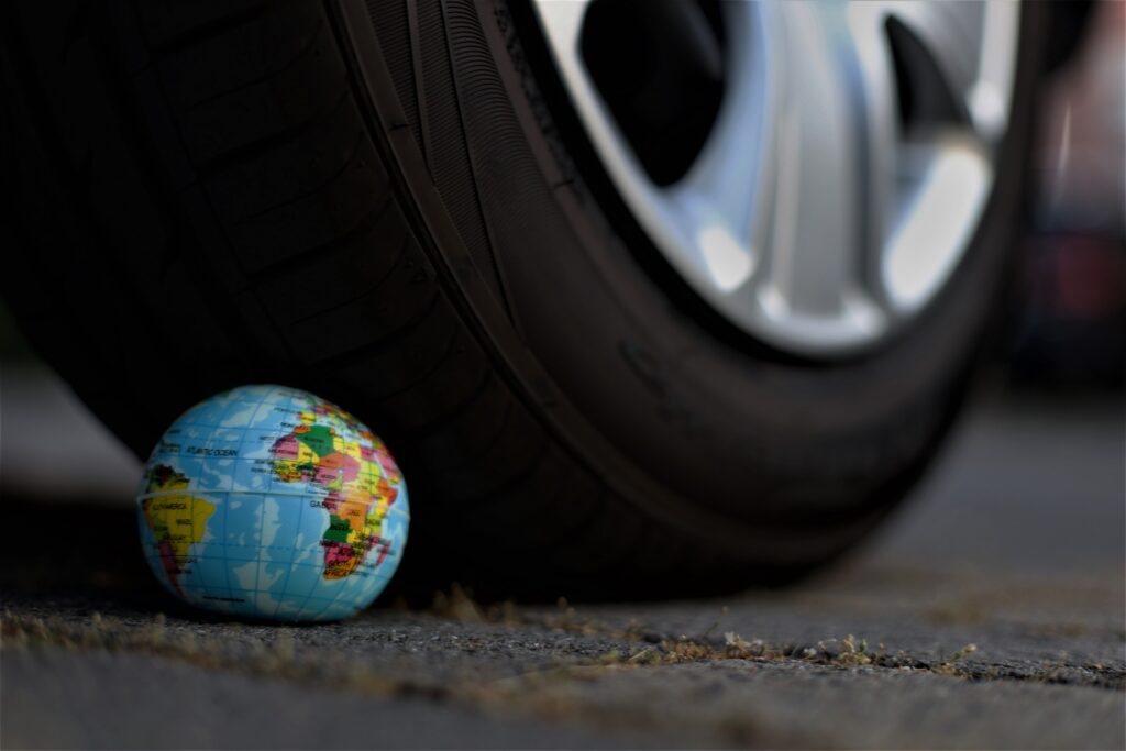 Un mappamondo schiacciato da una ruota di un'auto. Immagine simbolica