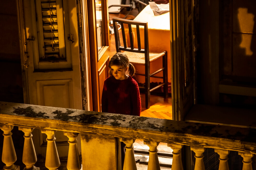 Una bambina dall'aria malinconica affacciata al balcone