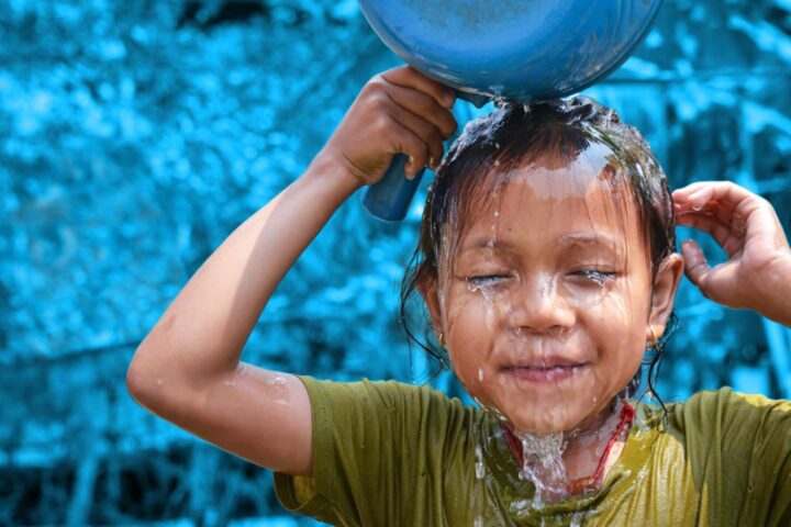 Un bambino asiatico si versa dell'acqua in testa per rinfrescarsi dal caldo estremo