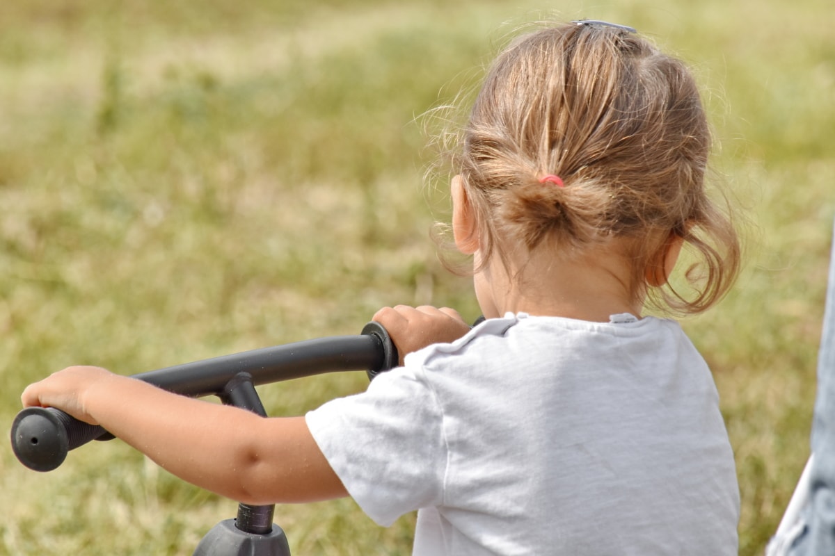 Una bambina di spalle nel verde