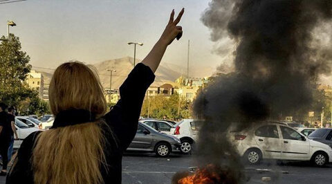 Una manifestante ripresa di spalle, mentre protesta contro il regime iraniano