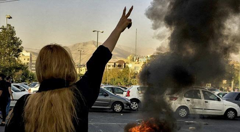 Una manifestante ripresa di spalle, mentre protesta contro il regime iraniano