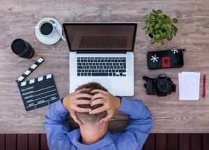 Un uomo si mette la testa tra le mani mentre lavora al computer