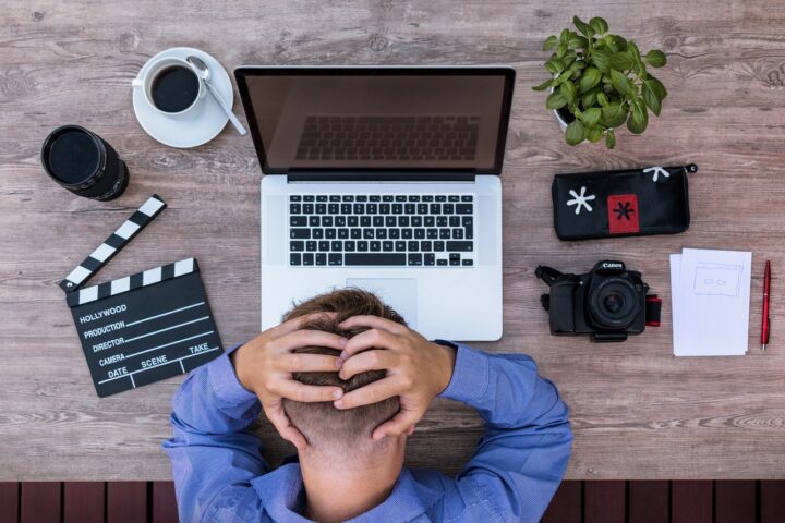 Un uomo si mette la testa tra le mani mentre lavora al computer