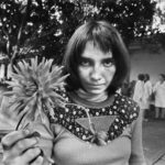 Graziella, una foto di Letizia Battaglia raffigurante una donna con un fiore in mano