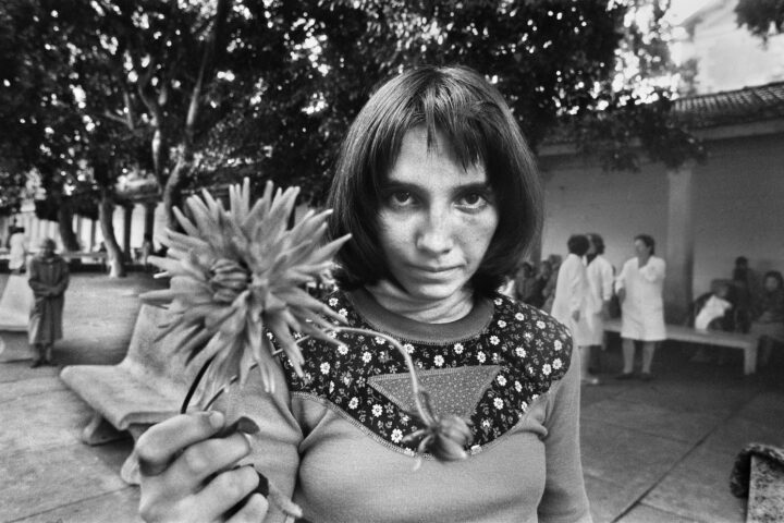 Graziella, una foto di Letizia Battaglia raffigurante una donna con un fiore in mano