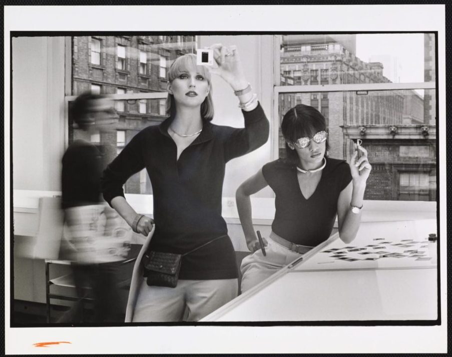 DUANE MICHALS, Two models in an office looking at negatives, 1976, Vogue, © Condé Nast