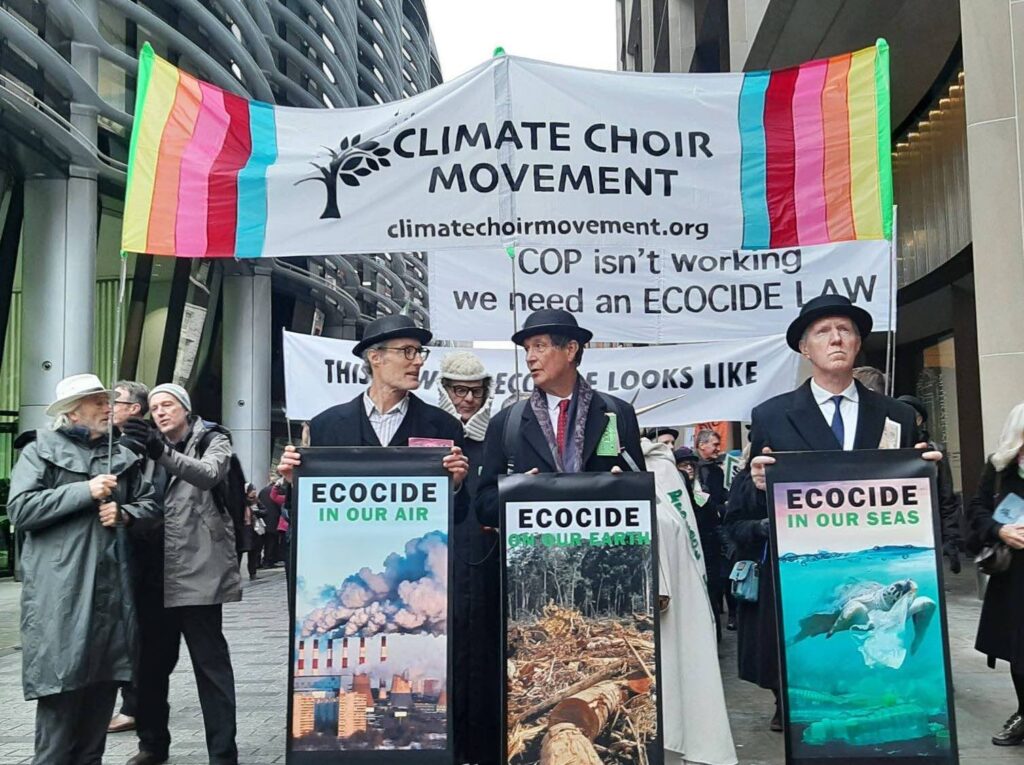 Un coro dei Climate Choir Movement in azione nel dicembre 2023, alla City di Londra. I partecipanti indossano le iconiche bombette