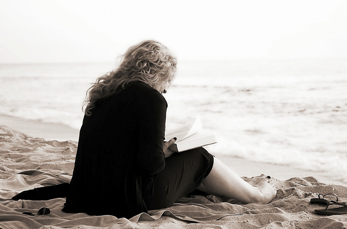 Una donna con un libro in riva al mare (Foto:PxHere)