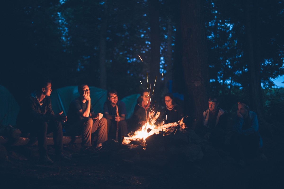 Un gruppo di giovani attorno a un falò, in un bosco. Anticamente, per molte popolazioni, accendere un fuoco era un rito legato all'arrivo dell'Autunno (Foto: Pixhere)