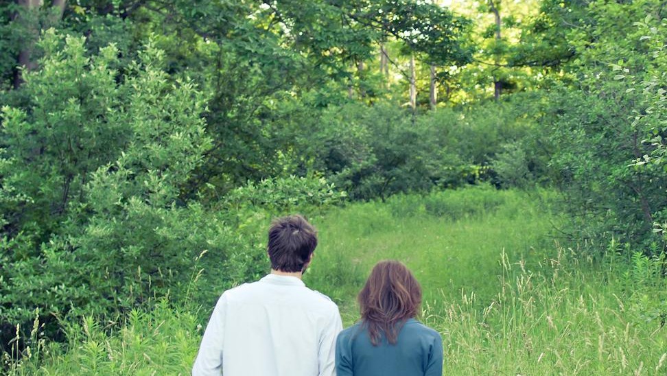 un uomo e una donna di spalle circondati da piante