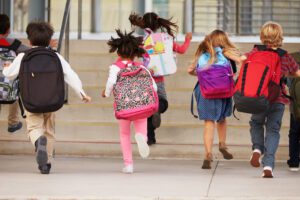 Latino sì, latino no. Bambini di spalle escono correndo dalla scuola