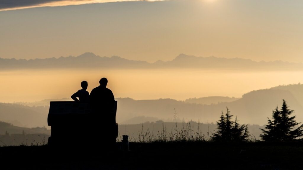 Il panorama dalla tappa di Sinio, sulla Strada romantica: una coppia osserva l'orizzonte, seduti sulla panchina, al tramonto 
