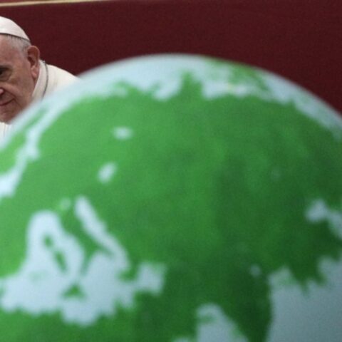 Papa Francesco accanto a un grande mappamondo.