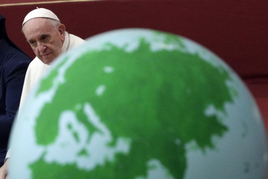 Papa Francesco accanto a un grande mappamondo.