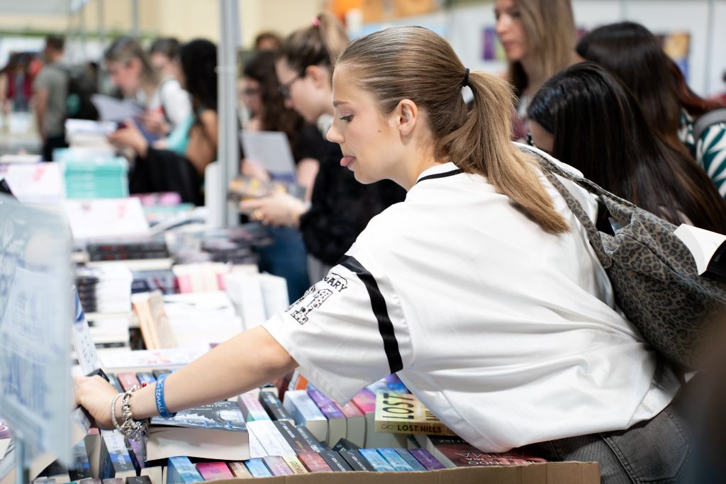 Una ragazza prende dei libri al Salone del Libro di Torino