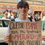 Maturità ribelle: un ragazzo con il cartello "Questo esame non mi rende maturo"