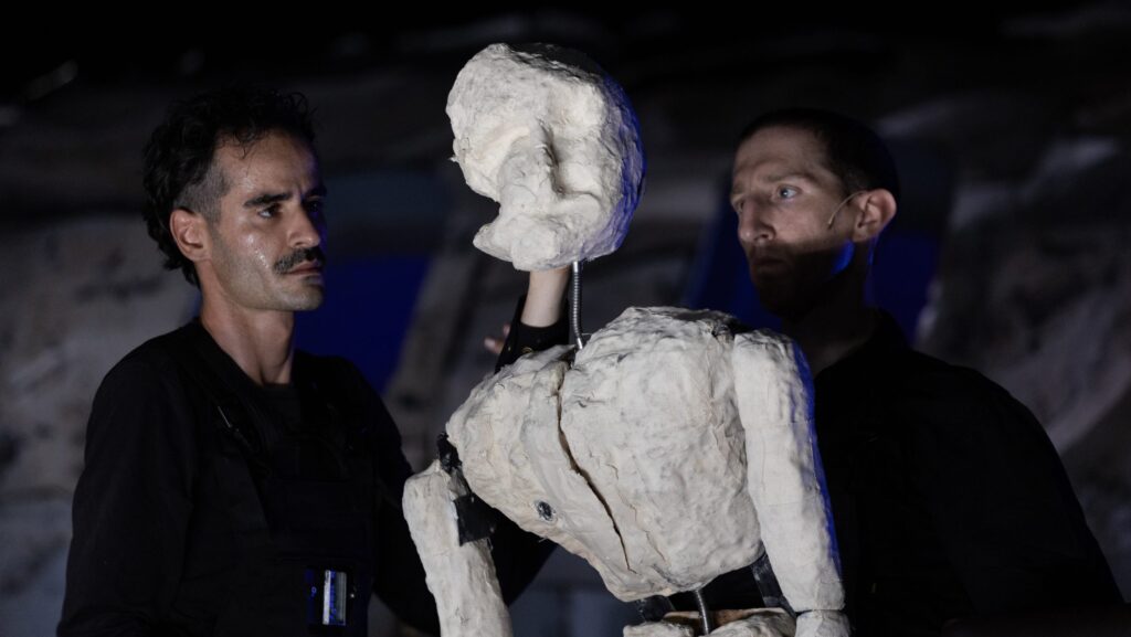 Umanità al limite: a teatro con "Oltre": una scena dello spettacolo con attori e puppet intorno alla fusoliera dell'aereo