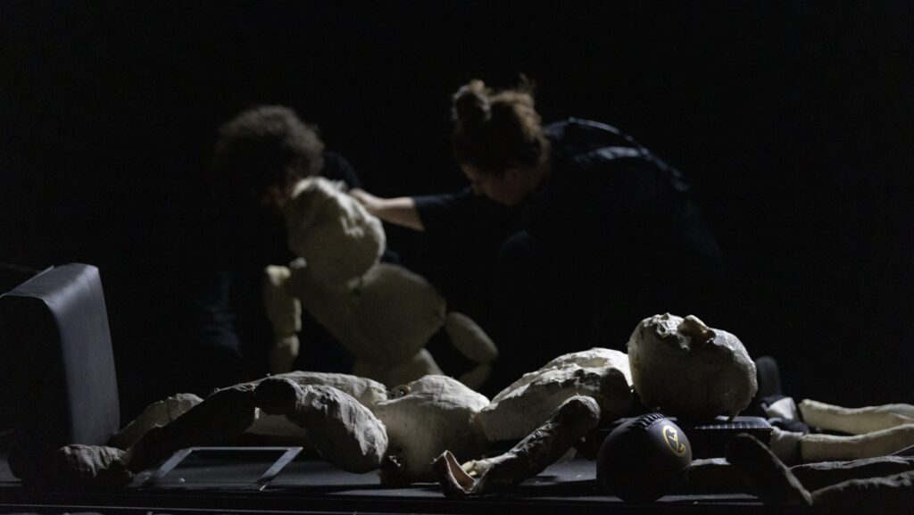 Umanità al limite: a teatro con "Oltre": una scena dello spettacolo con attori e puppet intorno alla fusoliera dell'aereo