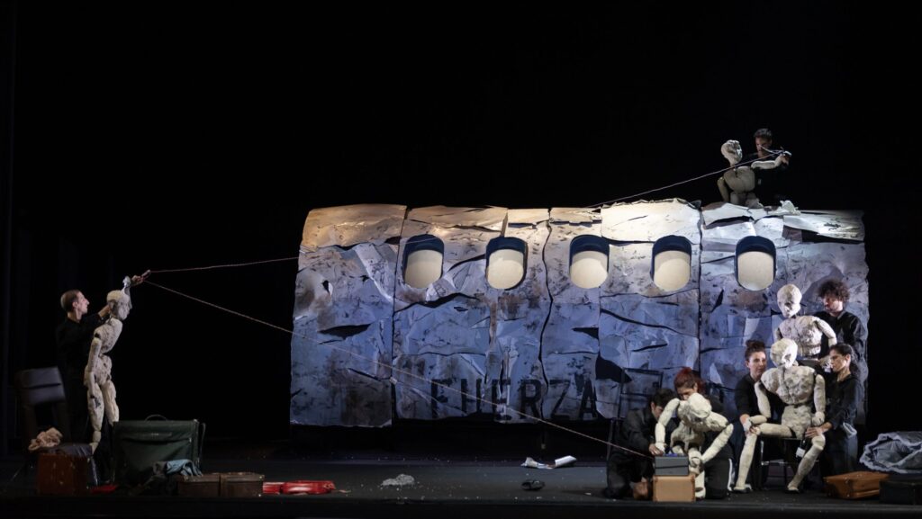 Umanità al limite: a teatro con "Oltre": una scena dello spettacolo con attori e puppet intorno alla fusoliera dell'aereo