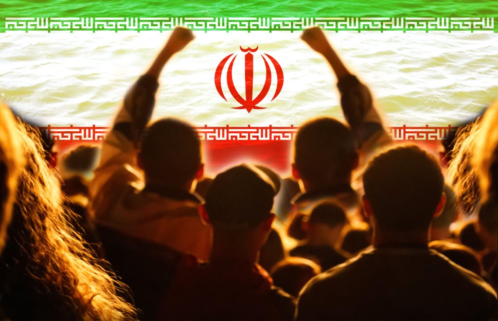Iran, l'ombra dell'escalation: manifestanti sullo sfondo della bandiera iraniana