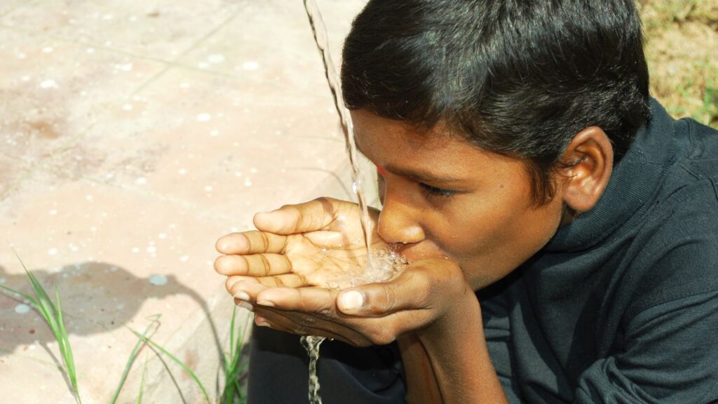 Cinque tendenze globali per la sostenibilità che dovete conoscere: un bambino che beve da una fonte d'acqua