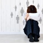 ragazzino rannicchiato nasconde il viso