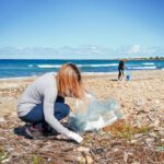 Una donna raccoglie rifiuti di plastica dalla spiaggia