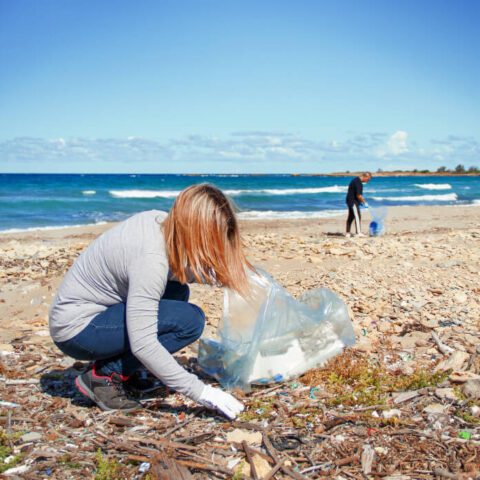 Una donna raccoglie rifiuti di plastica dalla spiaggia