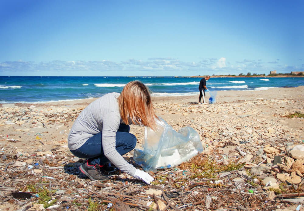 Una donna raccoglie rifiuti di plastica dalla spiaggia