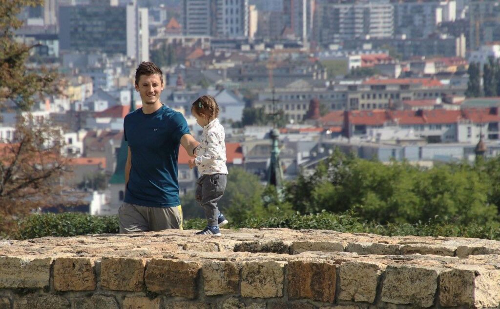 Un papà che sostiene una bambina mentre cammina sul muretto