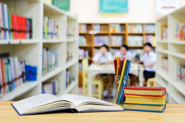 Primo piano di libri, sullo sfondo dei bambini all'interno di una biblioteca 