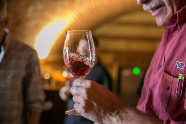 il primo piano di un calice di vino rosso, tenuto in mano da un uomo durante il Festival