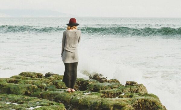 Una donna, di spalle su un promontorio, guarda il mare in tempesta